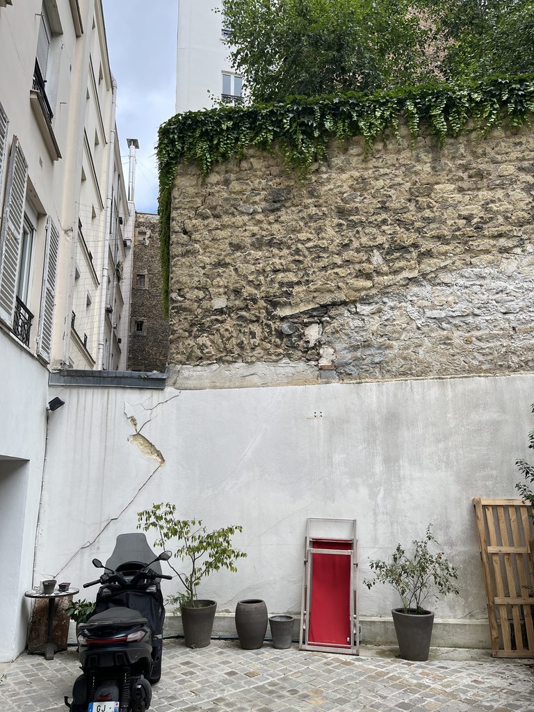 Fissures visibles sur un ancien mur en maçonnerie dans une cour parisienne